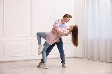 Photo of Happy couple dancing together near white wall at home