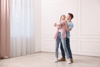 Photo of Happy couple dancing together near white wall at home. Space for text