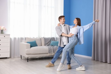 Photo of Happy young couple dancing together at home