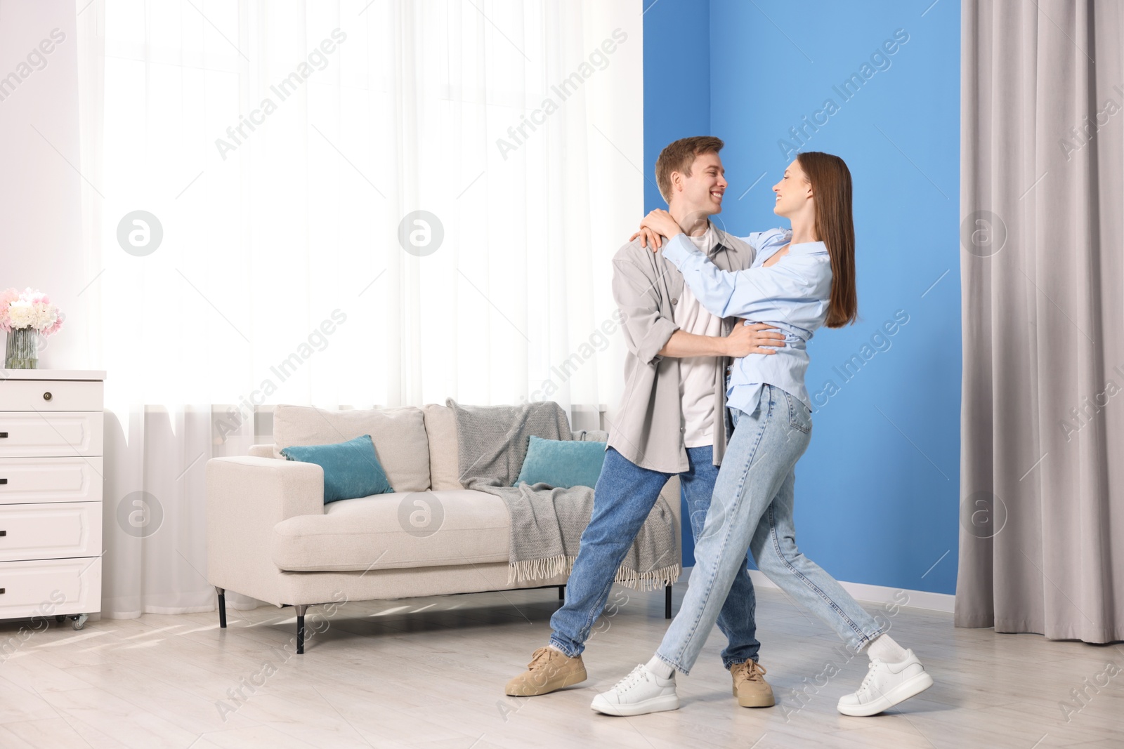 Photo of Happy young couple dancing together at home
