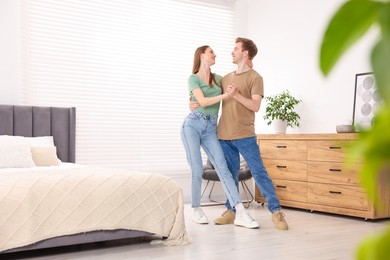 Photo of Happy young couple dancing together in bedroom