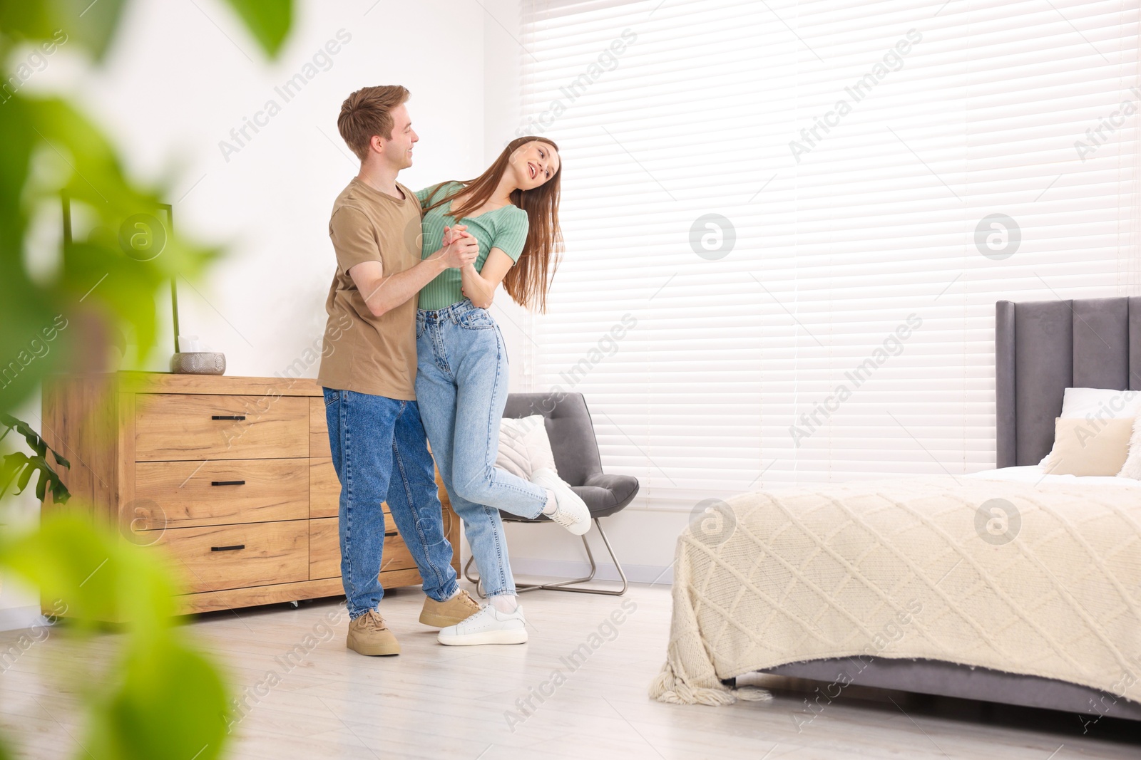 Photo of Happy young couple dancing together in bedroom
