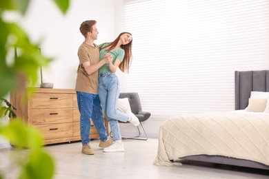 Photo of Happy young couple dancing together in bedroom