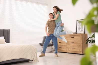 Photo of Happy young couple dancing together in bedroom