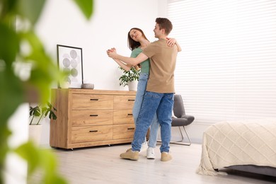 Photo of Carefree young couple dancing together at home