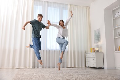 Photo of Happy young couple dancing together at home, low angle view