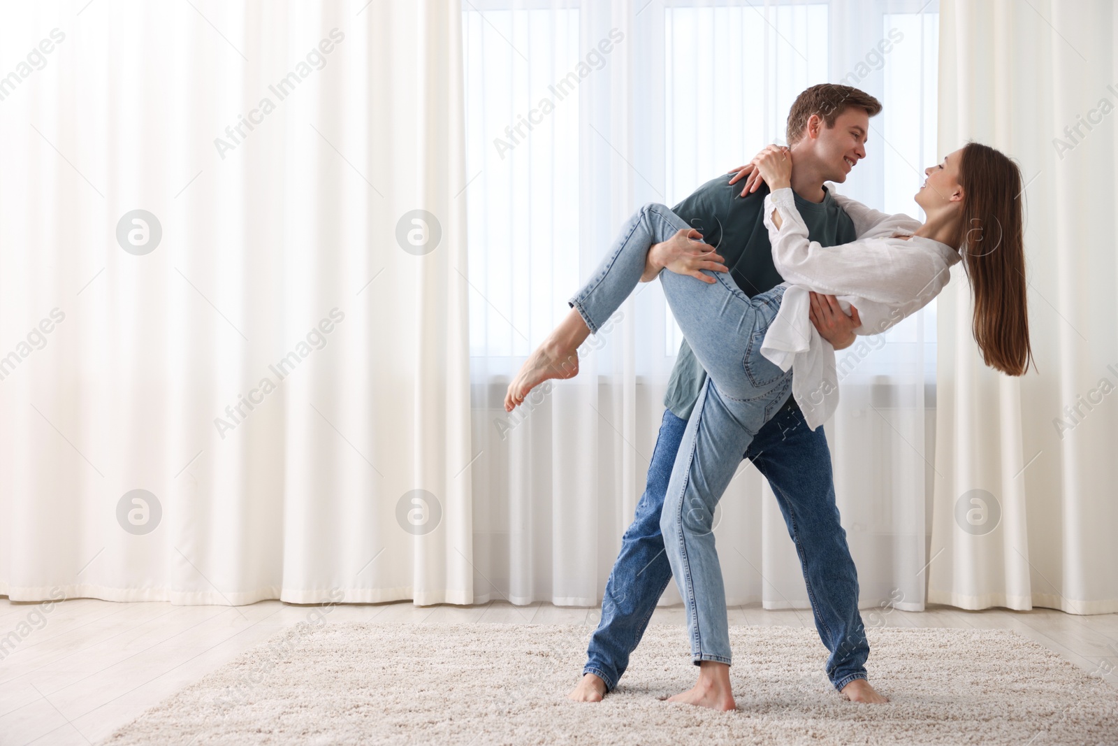 Happy young couple dancing together at home. Space for text Photo of Happy young couple dancing together at home. Space for text