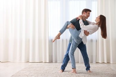 Photo of Happy young couple dancing together at home. Space for text
