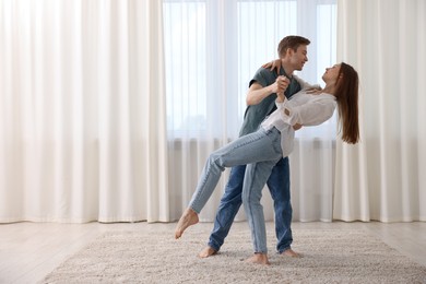 Photo of Happy young couple dancing together at home. Space for text