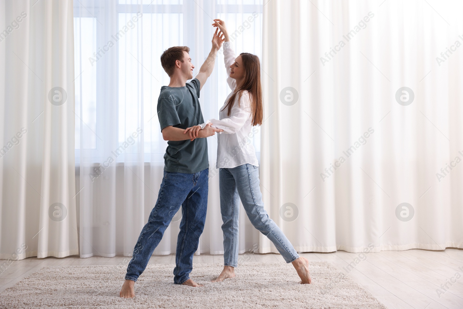 Photo of Happy young couple dancing together at home