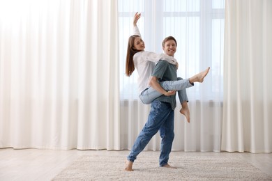 Photo of Happy young couple dancing together at home. Space for text