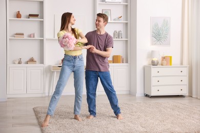 Photo of Happy young couple dancing together at home
