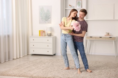 Photo of Young couple dancing together at home. Space for text