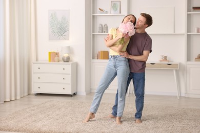 Photo of Happy young couple dancing together at home. Space for text