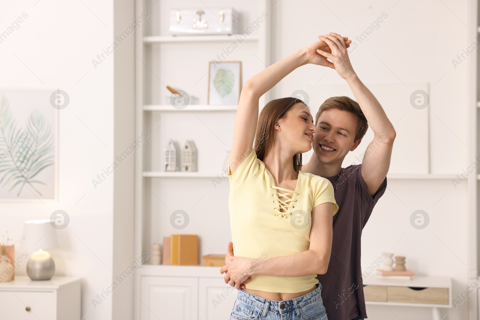 Photo of Happy young couple dancing together at home. Space for text