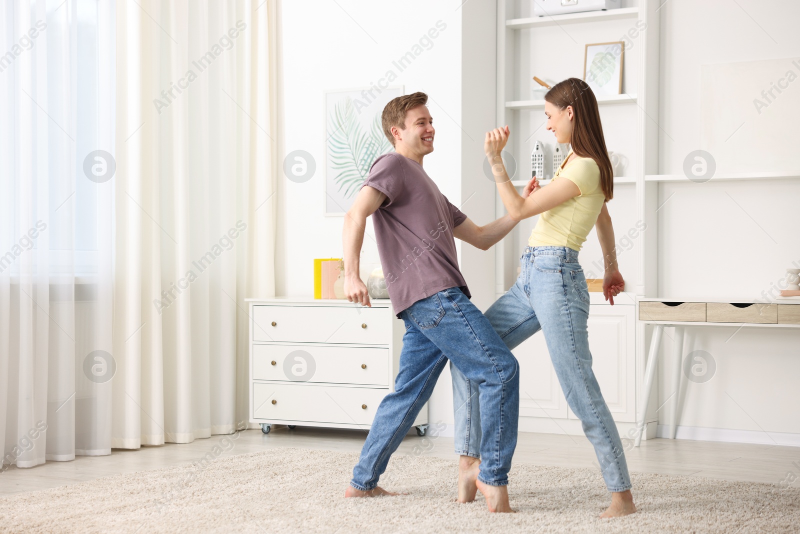 Photo of Happy young couple dancing together at home. Space for text