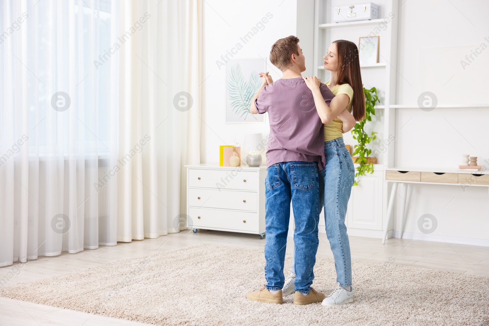 Photo of Young couple dancing together at home. Space for text