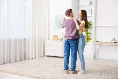 Photo of Young couple dancing together at home. Space for text