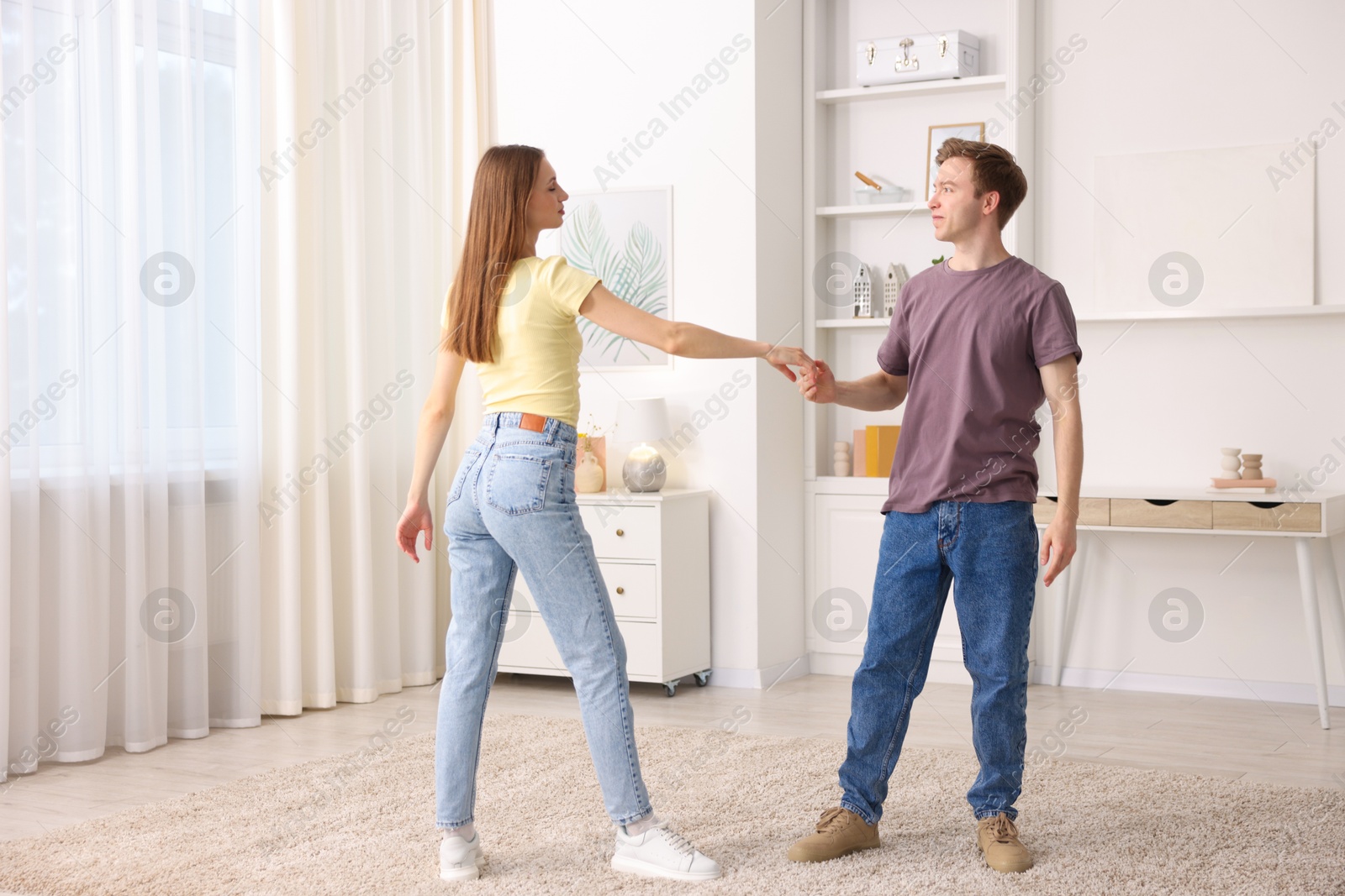 Photo of Carefree young couple dancing together at home
