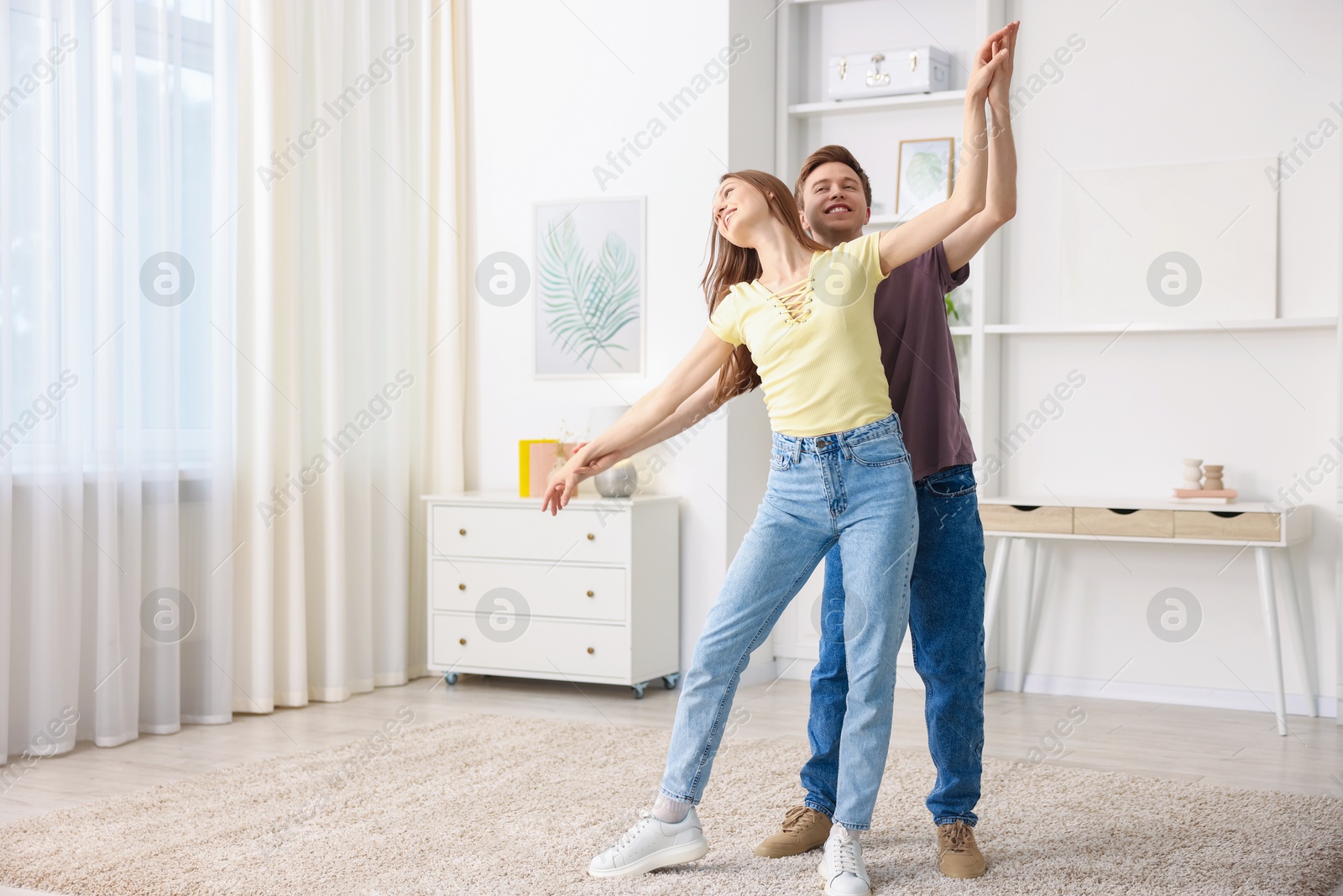 Photo of Happy young couple dancing together at home. Space for text