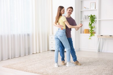 Photo of Happy young couple dancing together at home. Space for text