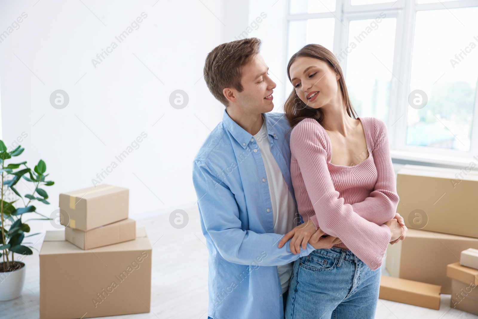 Photo of Young couple dancing and cardboard boxes at home. Moving day