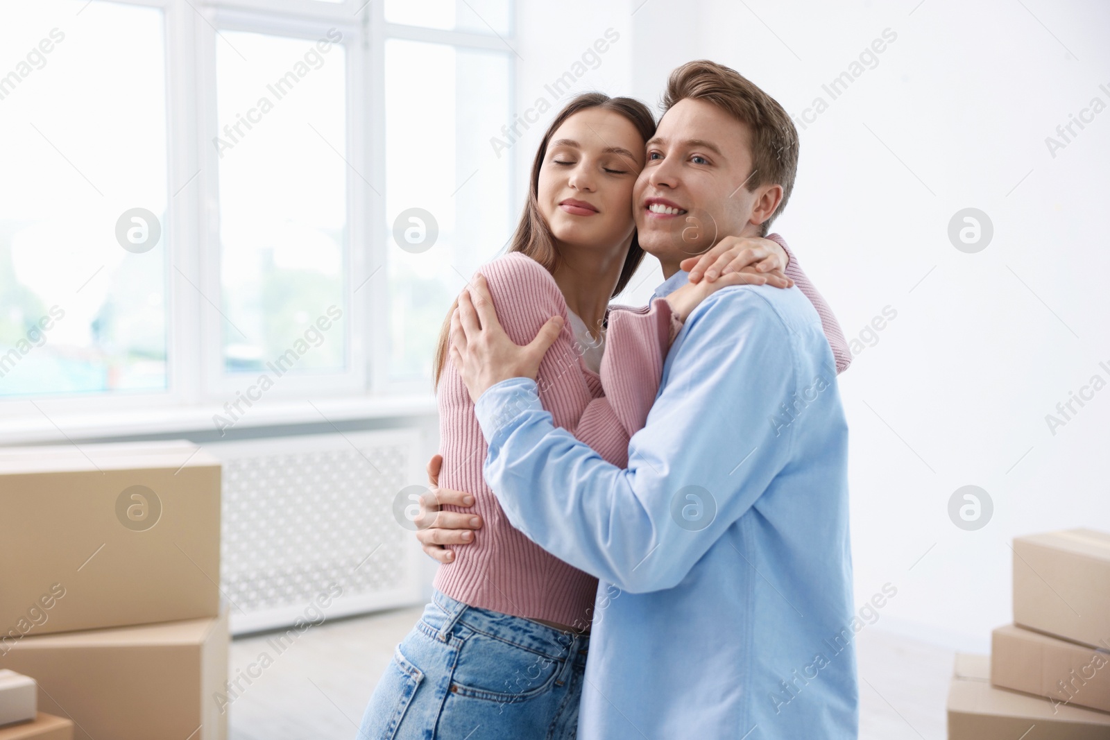 Photo of Happy young couple dancing and cardboard boxes at home. Moving day