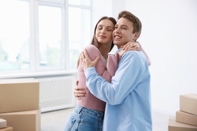 Photo of Happy young couple dancing and cardboard boxes at home. Moving day