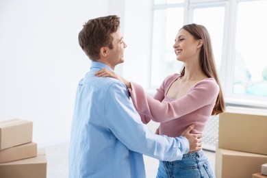 Photo of Happy young couple dancing and cardboard boxes at home. Moving day