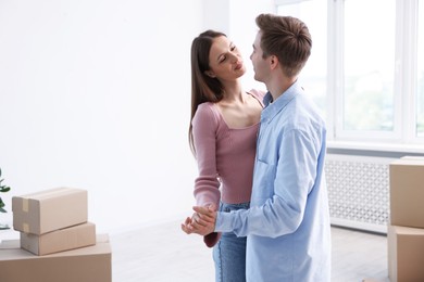 Photo of Young couple dancing and cardboard boxes at home. Moving day