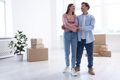 Photo of Happy young couple dancing and cardboard boxes at home, low angle view. Moving day