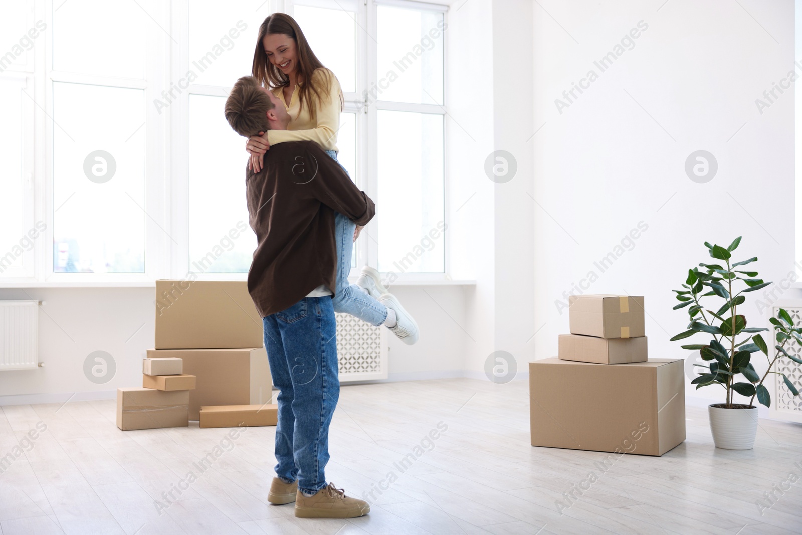 Photo of Happy young couple dancing and cardboard boxes at home. Moving day