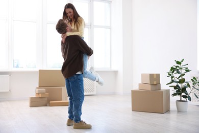 Photo of Happy young couple dancing and cardboard boxes at home. Moving day