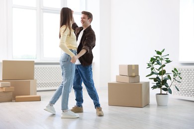 Photo of Happy young couple dancing and cardboard boxes at home, low angle view. Moving day