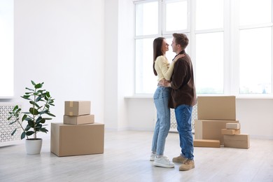 Photo of Happy young couple dancing and cardboard boxes at home. Moving day