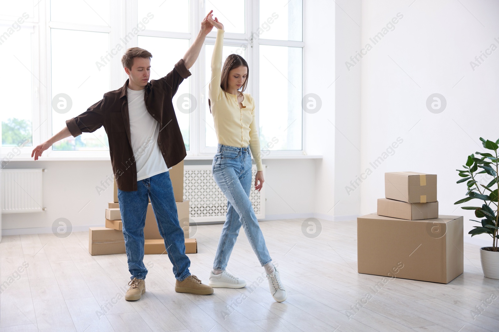 Photo of Young couple dancing and cardboard boxes at home. Moving day