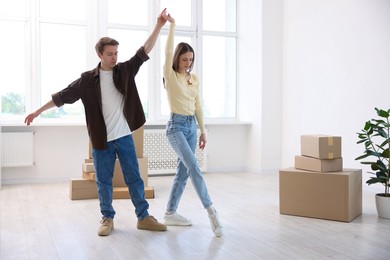 Photo of Young couple dancing and cardboard boxes at home. Moving day