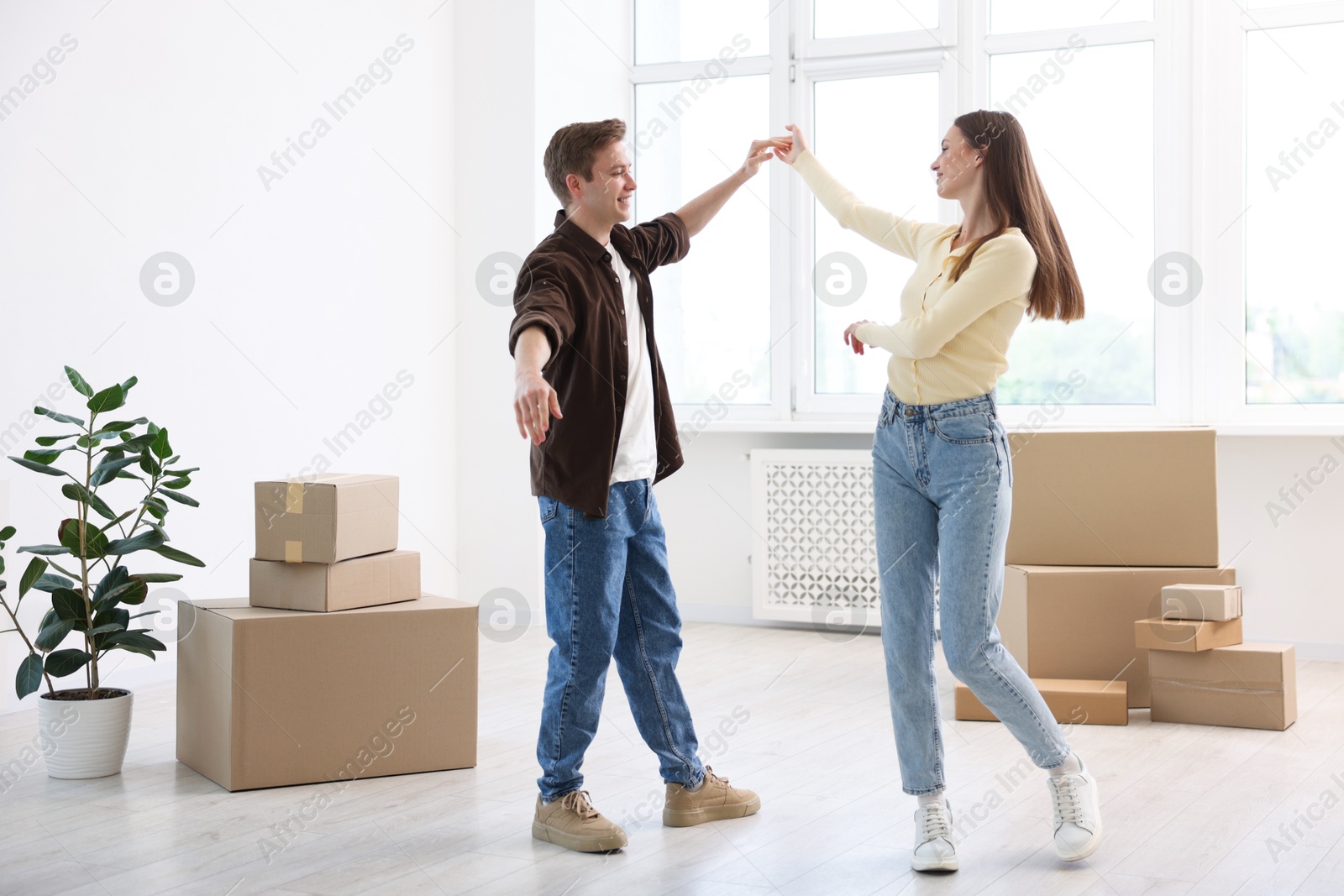 Photo of Happy young couple dancing among moving boxes at home