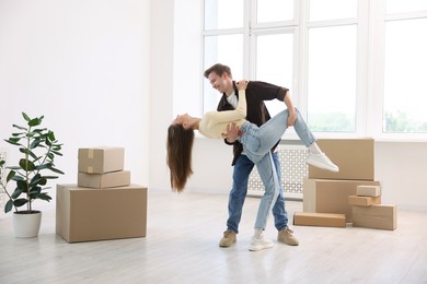 Photo of Happy young couple dancing among moving boxes at home