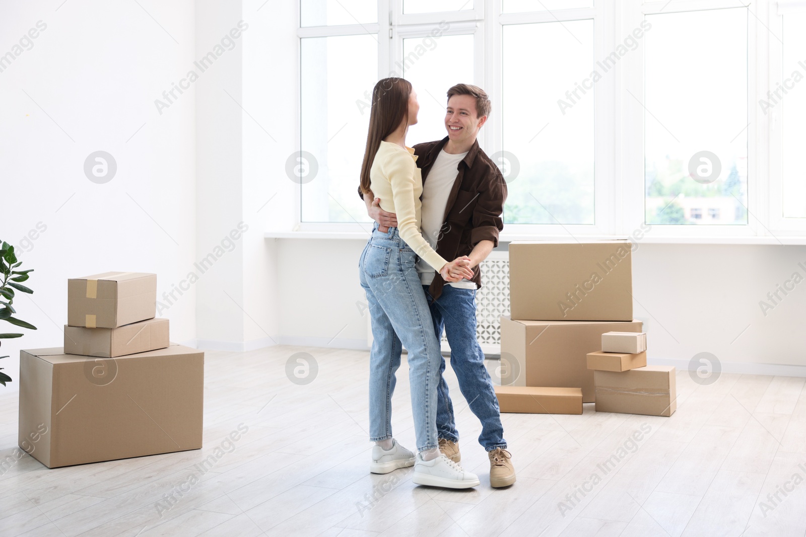 Photo of Happy young couple dancing among moving boxes at home