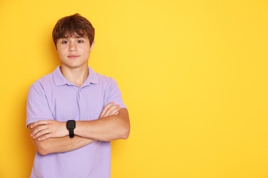 Photo of Cute teenage boy with crossed arms on yellow background. Space for text