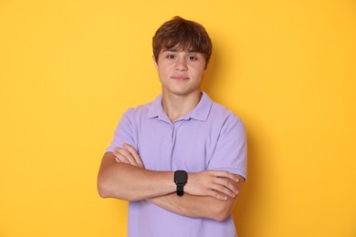 Photo of Cute teenage boy with crossed arms on yellow background