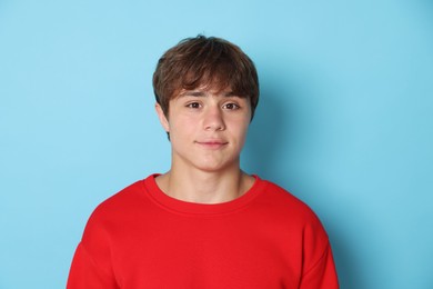 Photo of Portrait of cute teenage boy on light blue background