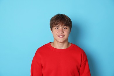 Photo of Portrait of smiling teenage boy on light blue background