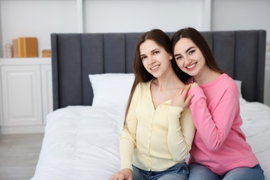 Photo of Happy friends hugging each other on bed at home, space for text