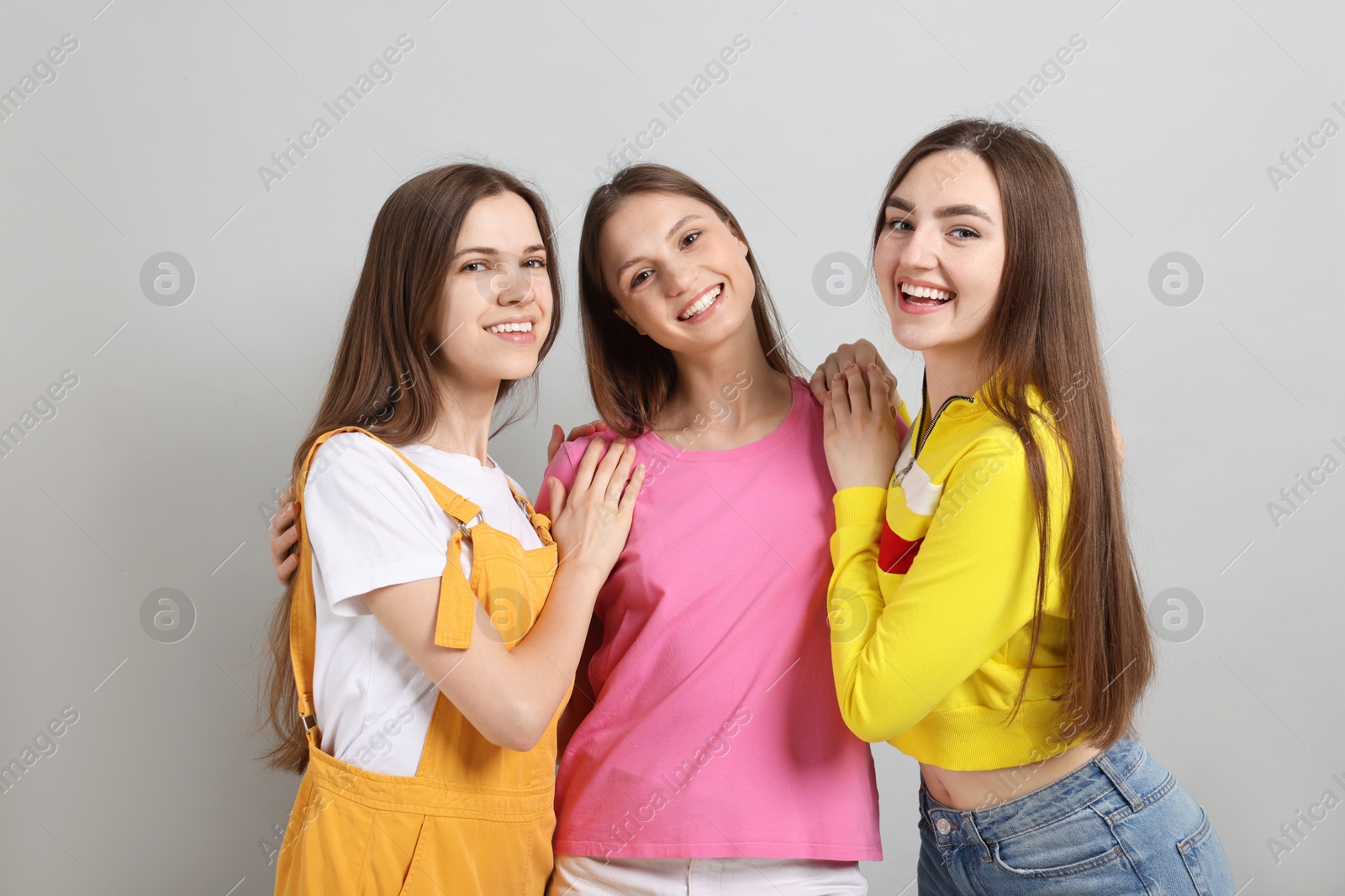 Friends hugging each other on light grey background Photo of Friends hugging each other on light grey background
