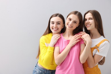 Photo of Friends hugging each other on light grey background, space for text