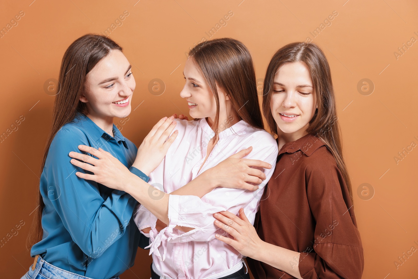 Photo of Friends hugging each other on pale brown background