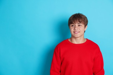 Photo of Smiling teenage boy on light blue background. Space for text