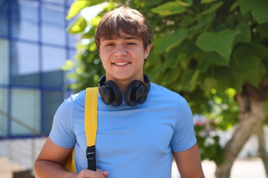 Photo of Portrait of smiling teenage boy with headphones on city street